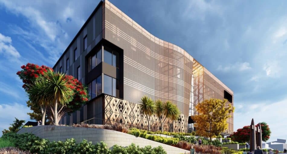 A modern multi-storey courthouse building with a distinctive perforated bronze façade that curves elegantly across its exterior. The design incorporates Māori-inspired patterns along the lower level and native landscaping with trees and plants in the foreground. The building sits on a landscaped slope under a bright blue sky with scattered clouds, creating a striking architectural presence.