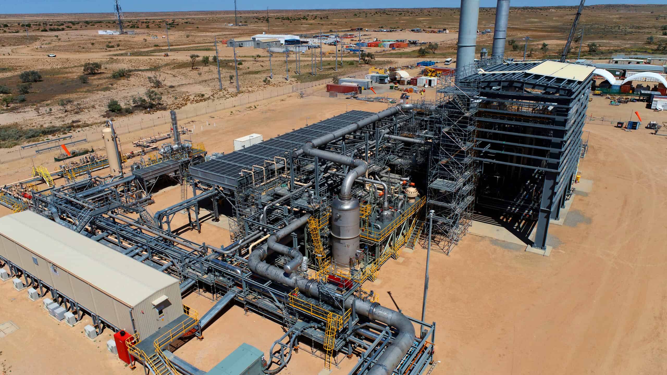 Aerial view of a gas plant surrounded by arid desert landscape, showcasing industrial structures and sparse vegetation.