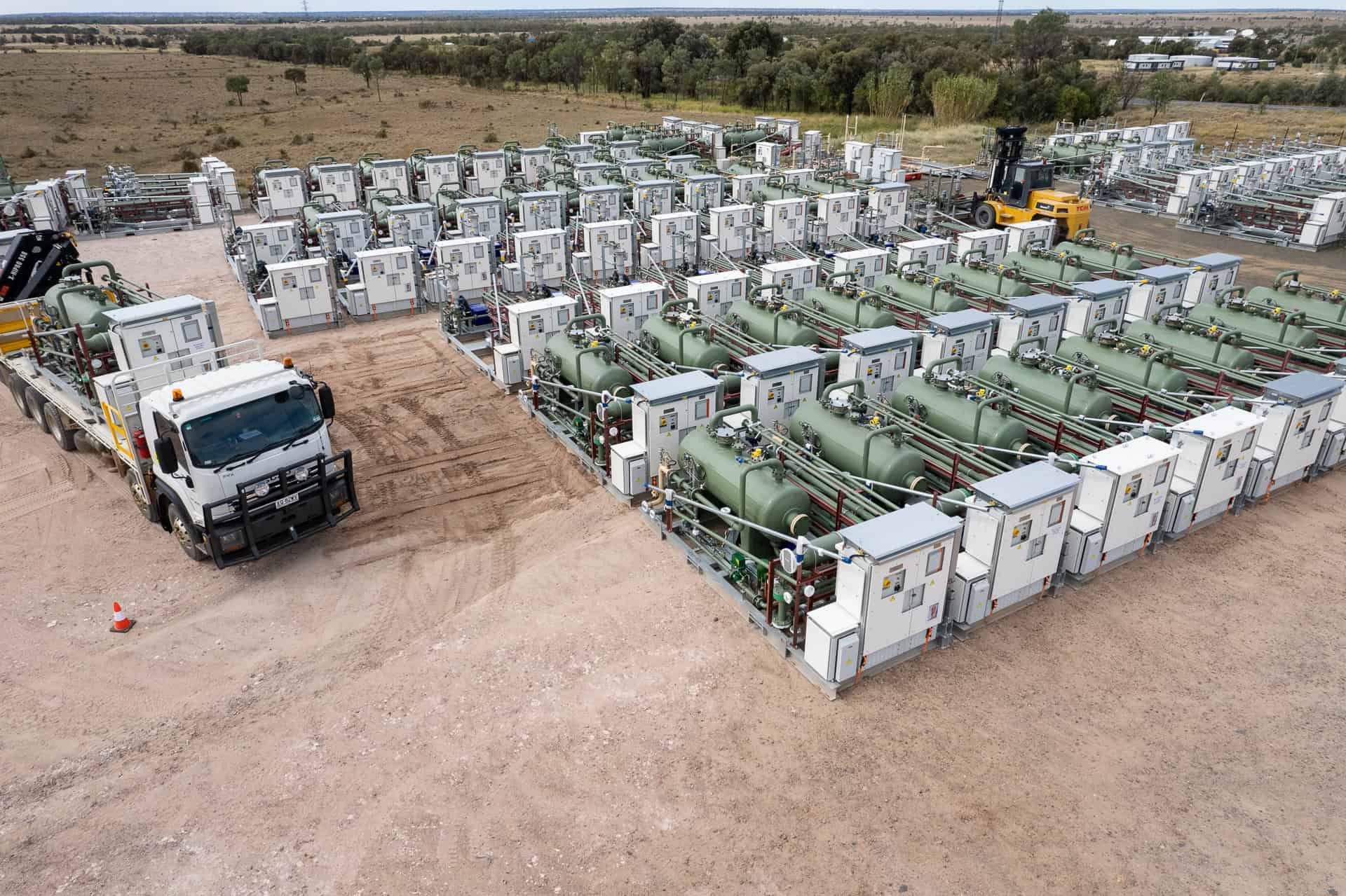 A large truck parked beside a large storage tank in an industrial setting.