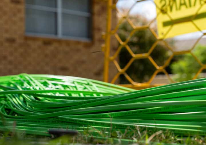 A disorganized heap of green plastic pipes, varying in length and diameter, resting on a neutral background